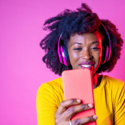 A guide to YouTube's algorithm 2023 - woman with headphones and phone in front of a pink background