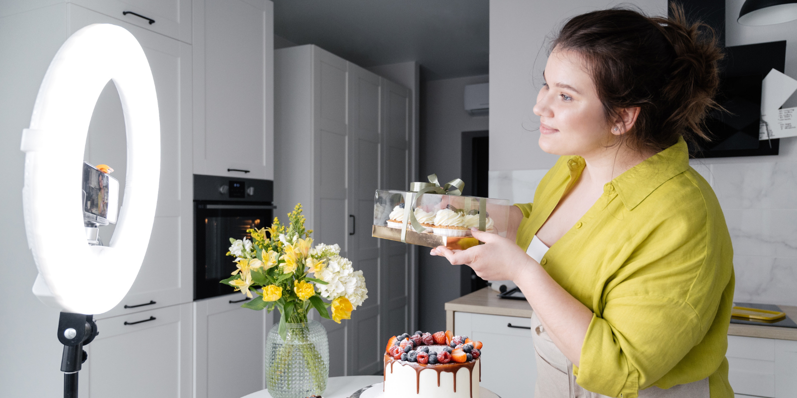 woman holding cupcakes in a kitchen in front of camera - how to find youtube influencers